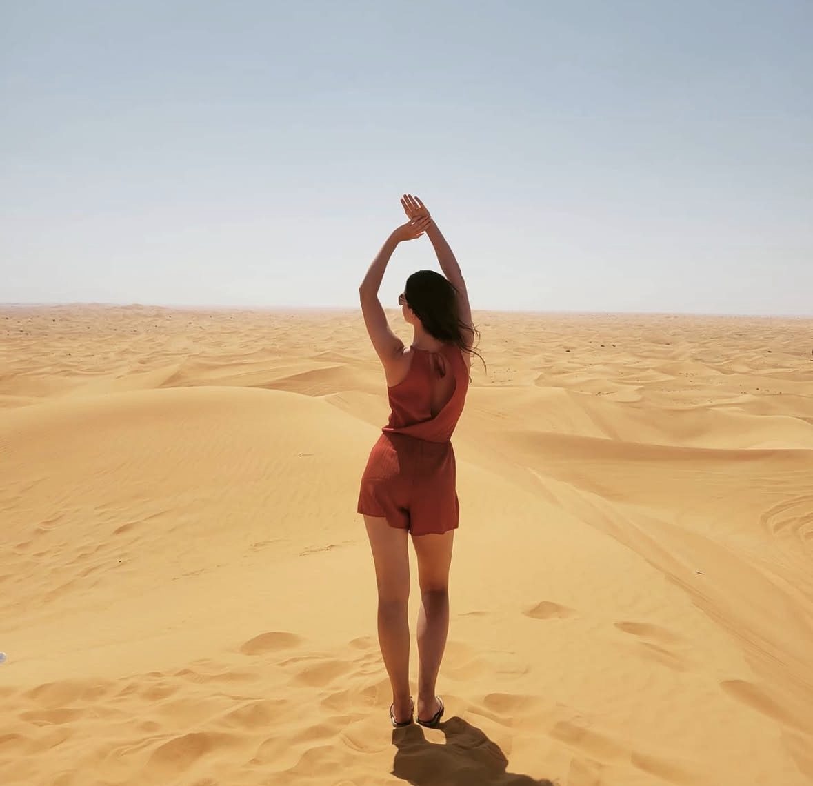 Golden sunset light casting long shadows across the red dunes of Lahbab Desert in Dubai during peak season